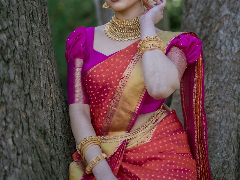 Magenta silk blouse with puff sleeves worn with an orange pattu saree